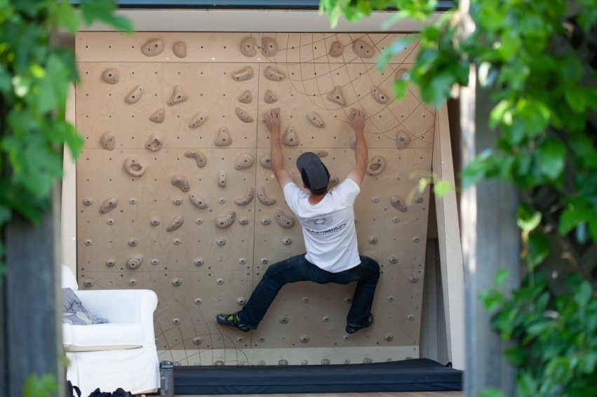climbing wall pictured at end of garden in summer house with climber on a circuit problem