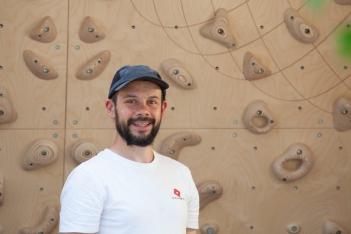 Piers Chapman portrait with his home climbing wall in the background